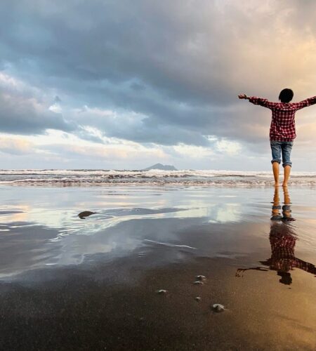 a man stands on a beach with his arm outstretched
