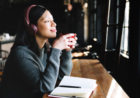 a woman listens to a podcast and sips a cup of coffee