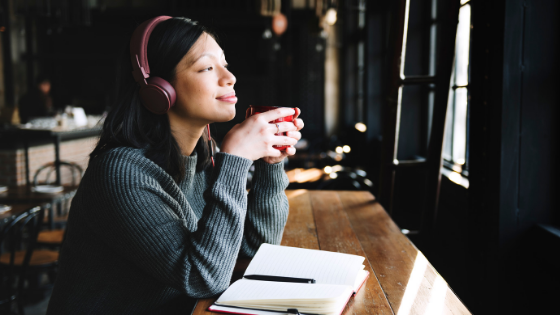 a woman listens to a podcast and sips a cup of coffee