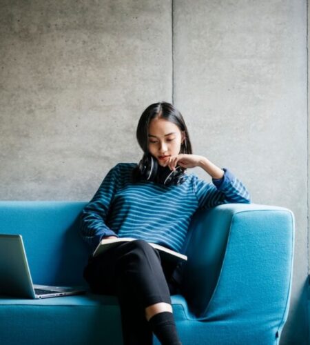 a woman sits on a couch and reads a book