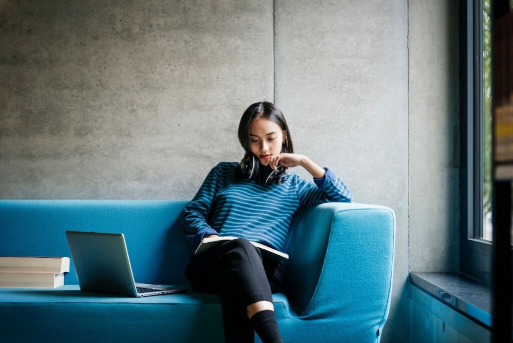 a woman sits on a couch and reads a book